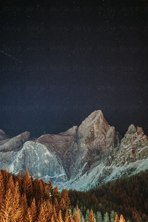 Italian Mountain Peaks At Night With Illuminated Forest By Stocksy