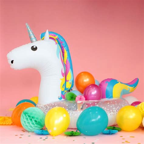 An Inflatable Unicorn Surrounded By Balloons And Confetti On A Pink