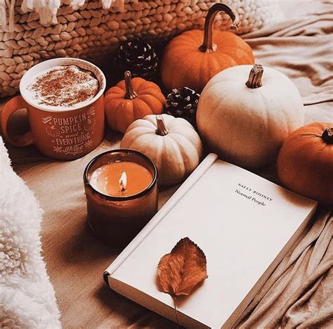 An Open Book Sitting On Top Of A Bed Next To Some Pumpkins And Candles