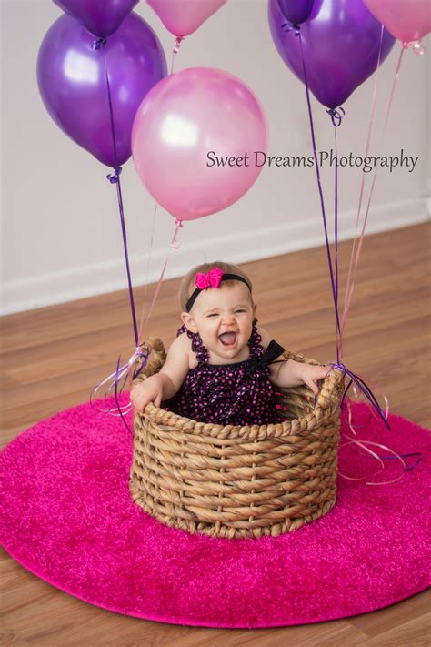 one year old girl birthday indoor photo shoot with balloons and her in a basket facebo