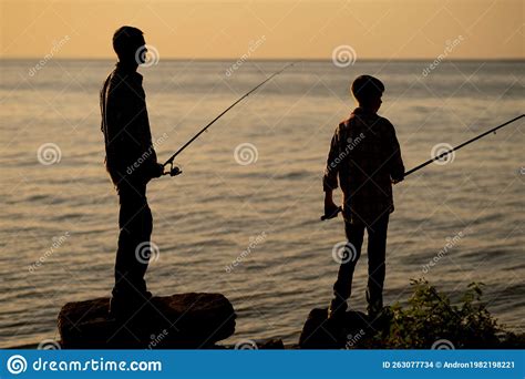 Silueta De Padre E Hijo Pescando Al Atardecer En Verano En El Mar Foto