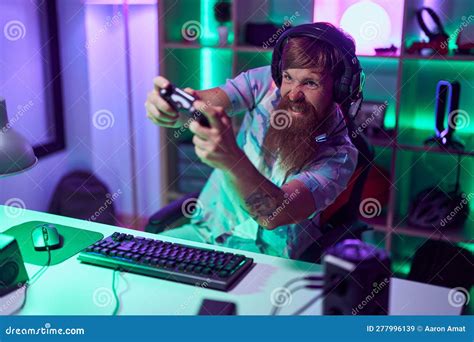 Young Redhead Man Streamer Playing Video Game Using Smartphone At Gaming Room Stock Image