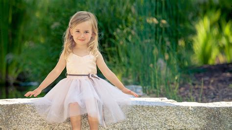 Cute Little Girl Is Wearing White Dress Sitting On Stone Pavement In