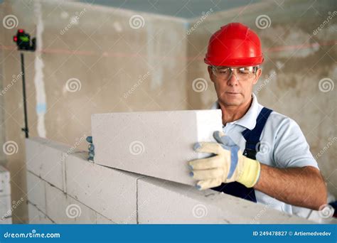 Bricklayer Or Mason Lays Bricks To Construct Wall Of Autoclaved Aerated