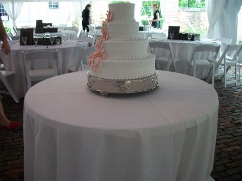 A Wedding Cake Sitting On Top Of A Table Covered In White Cloths And