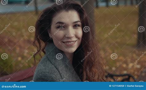 Young Brunette Gir In Coat Looking At Camera And Smiling In Slow Motion