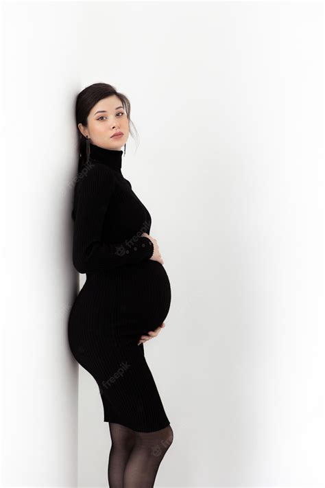 premium photo pregnant brunette in a black dress with a neck on a white background