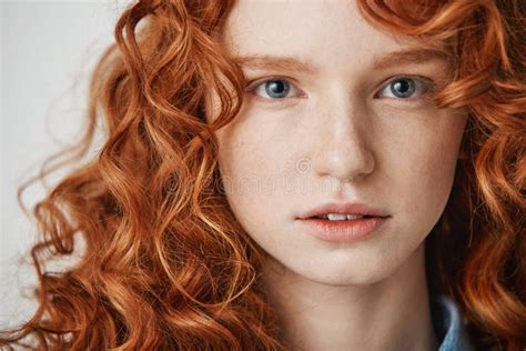 Close Up Of Beautiful Natural Ginger Girl With Freckles Looking At Camera White Background