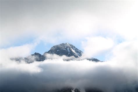 Thick Clouds Envelop A Tall Mountain Peak Partly Obscuring The View