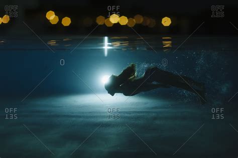 A Girl Swimming Underwater In A Pool At Night Stock Photo Offset