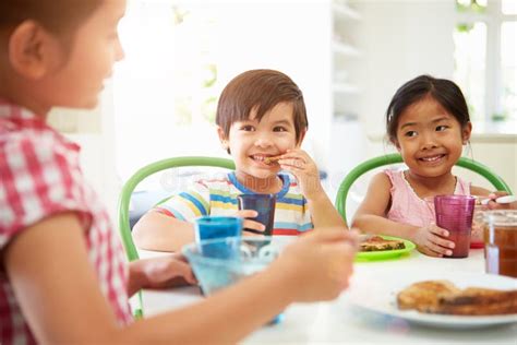 Three Asian Children Having Breakfast Together In Kitchen Stock Image