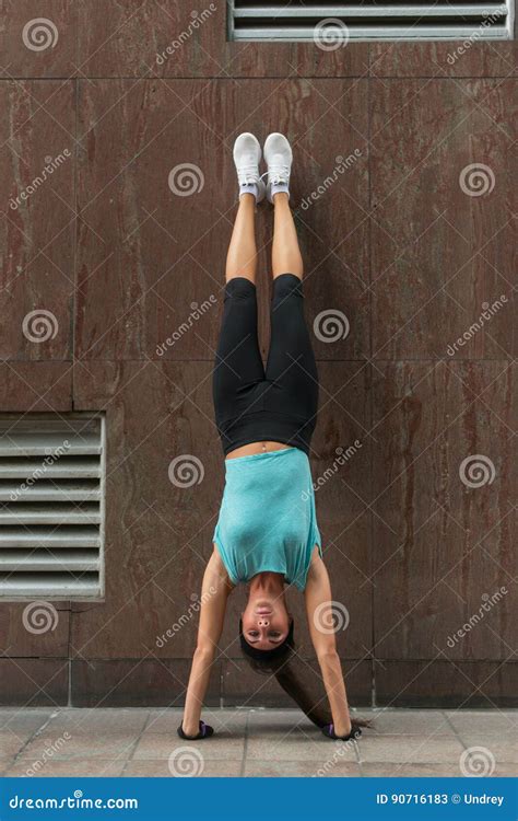 Young Woman Doing Handstand Exercise Against The Wall On The City