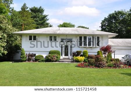Gardner architects green living homeplanners, l.l.c. Suburban High Ranch Style Home Landscaped With Flowers Plants Shrubs Bushes Sunny Blue Sky Day ...
