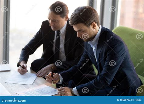 Successful Businessmen In Suits Signing Contract Partnership Agreement