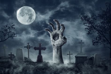 Zombie Hand Rising Out Of A Graveyard In Spooky Night Stock Photo