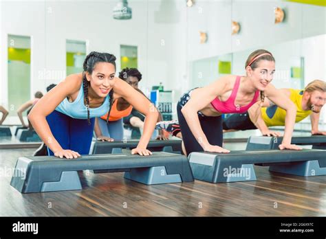 Determined Young Women Exercising Push Ups On Aerobic Stepper Platforms