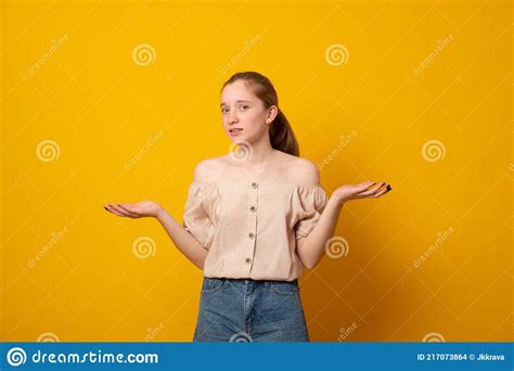 Puzzled Girl Spreads Hands With Doubtover Yellow Background Teen