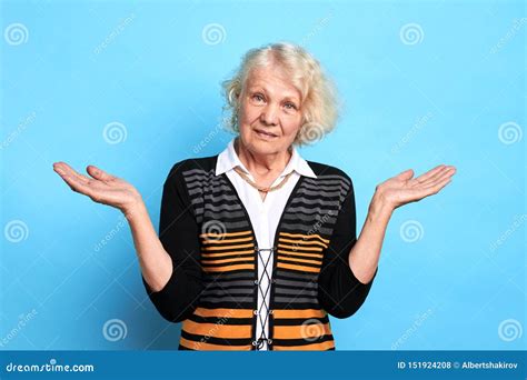 Beautiful Old Woman In Stylish Clothes Is Shrugging Shoulders Stock