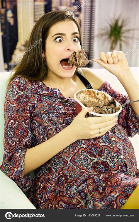 Смешная красивая беременная женщина ест большую ложку шоколадного мороженого стоковое фото