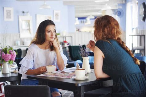Two Women Talking And Drinking Coffee At Cafe Stock Photo