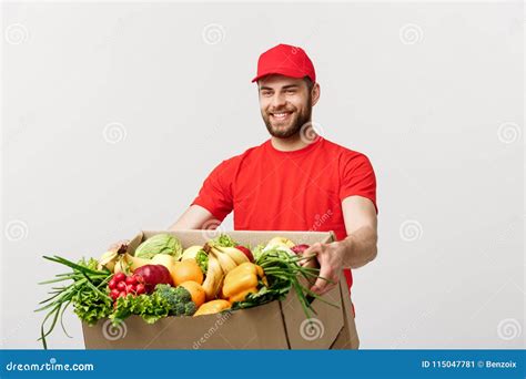 delivery concept handsome caucasian grocery delivery courier man in red uniform with grocery