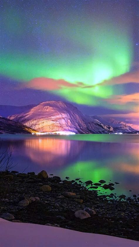 The Aurora Are Illuminating The Snow Covered Mountain Below