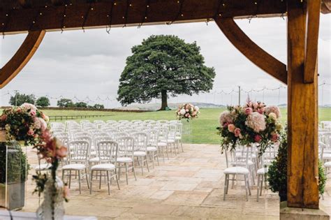 An Outdoor Ceremony Setup With White Chairs And Pink Flowers