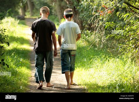 Two Young Boys Walking Along A Forest Track In Their Bare Feet Stock
