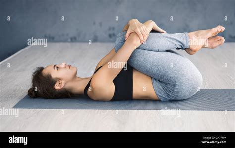 Woman Practicing Yoga Lying In Knees To Chest Pose Stock Photo Alamy