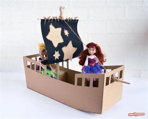 There Is A Cardboard Boat With Two Dolls In It And One Doll On The Ship