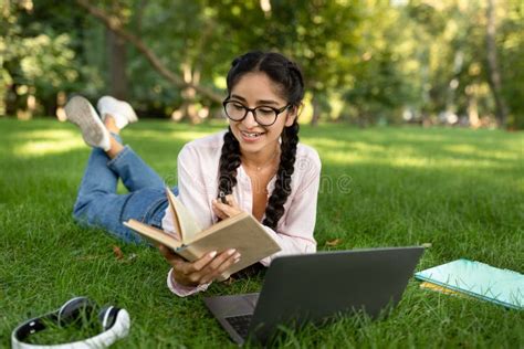 Happy Indian Student Girl In Eyeglasses Reading Book Outdoors