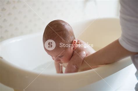 Unrecognizable Mother Holding Her Baby Son Bathing Him In Small White