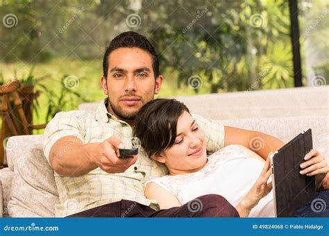 Happy Couple Cuddling And Sitting On The Couch Watching Tv Royalty Free