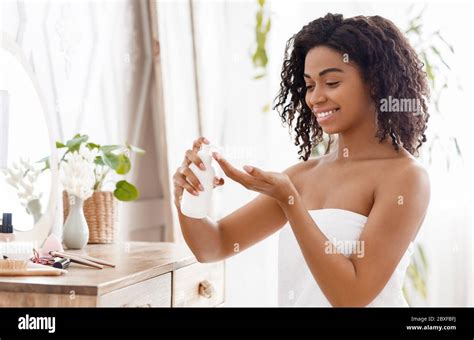 Skin Moisturizing Smiling African Woman Applying Body Lotion In Bedroom At Home Stock Photo Alamy