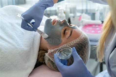 Beautician Applying Facial Mask For Female Client At Spa Salon Stock