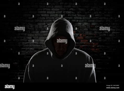 An Evil Looking Man With A Hidden Face And Wearing A Hoodie Stands Intimidatingly Against An