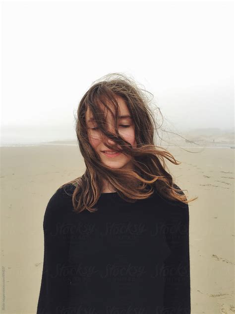 Portrait Of Twelve Year Old Girl On Beach Eyes Closed With Hair Covering Face By Stocksy