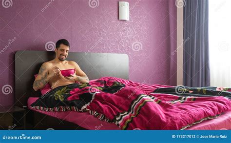macho tattoo muscular guy sitting in bed of the hotel having breakfast with nude chest lonely