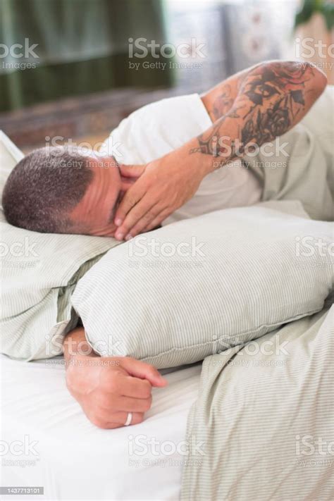 Man Lying In Bed In Morning And Rubbing Eyes With Hand Stock Photo