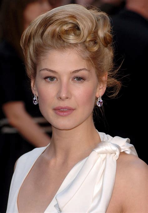 A Woman With Blonde Hair Wearing A White Dress And Diamond Earrings On