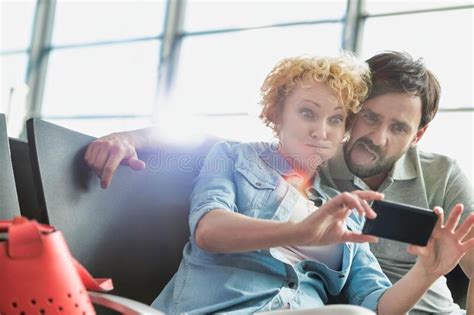 Portrait Of Mature Couple Taking Selfie While Waiting For Boarding In Airport Stock Image