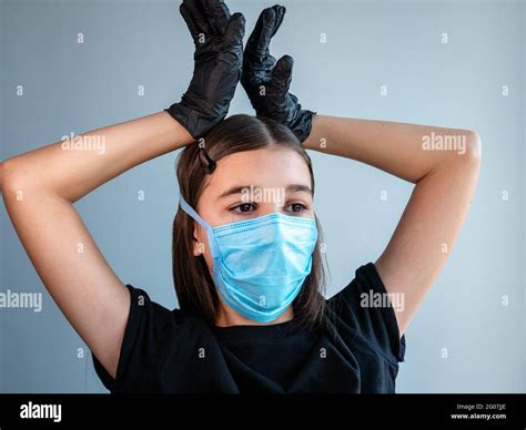 Female Teenage Girl In A Blue Protective Medical Face Mask Shows Corona