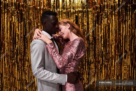 Side View Of Young Romantic Multiracial Couple In Stylish Apparel Embracing While Celebrating