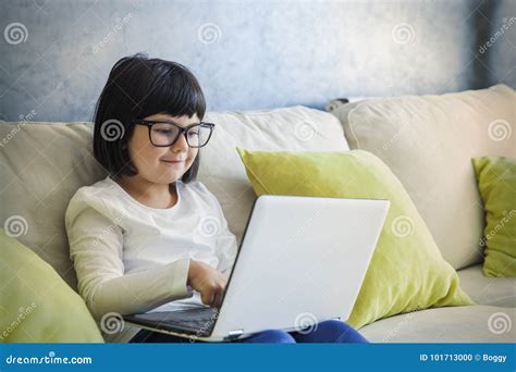 Black Hair Little Girl With Glasses Using Her Laptop While Sitting On