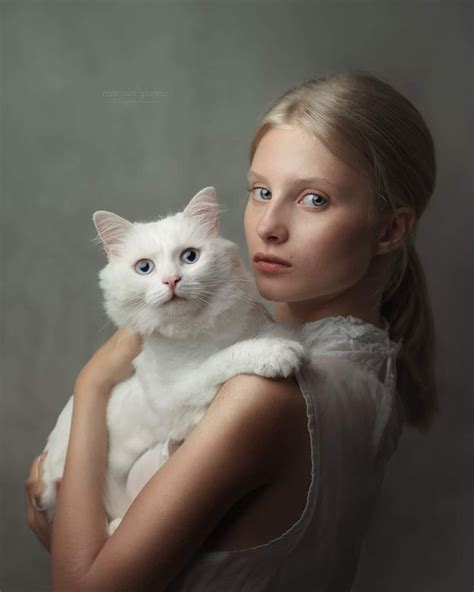 A Woman Is Holding A White Cat In Her Arms And Looking At The Camera