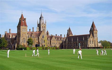 A Group Of Men Playing A Game Of Cricket On A Field In Front Of A Large