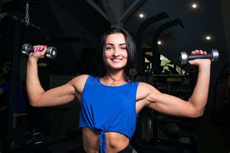 Young Girl With Sexual Inflated Figure In The Gym Dumbbell Lifts Pushing Hands Stock Image
