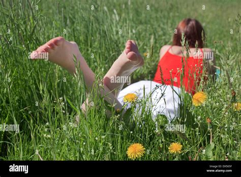 Young Barefoot Woman Lying On Her Stomach In A Flowering Spring Meadow