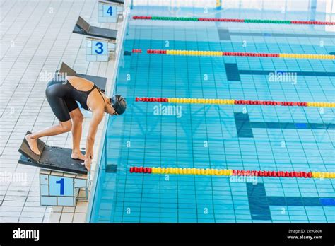 Professional Female Swimmer Preparing And Jumping Off The Starting