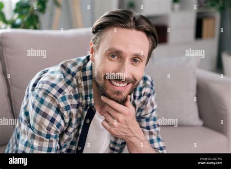 Photo Of Pretty Positive Mature Guy Dressed Checkered Shirt Smiling Sitting Couch Arm Chin
